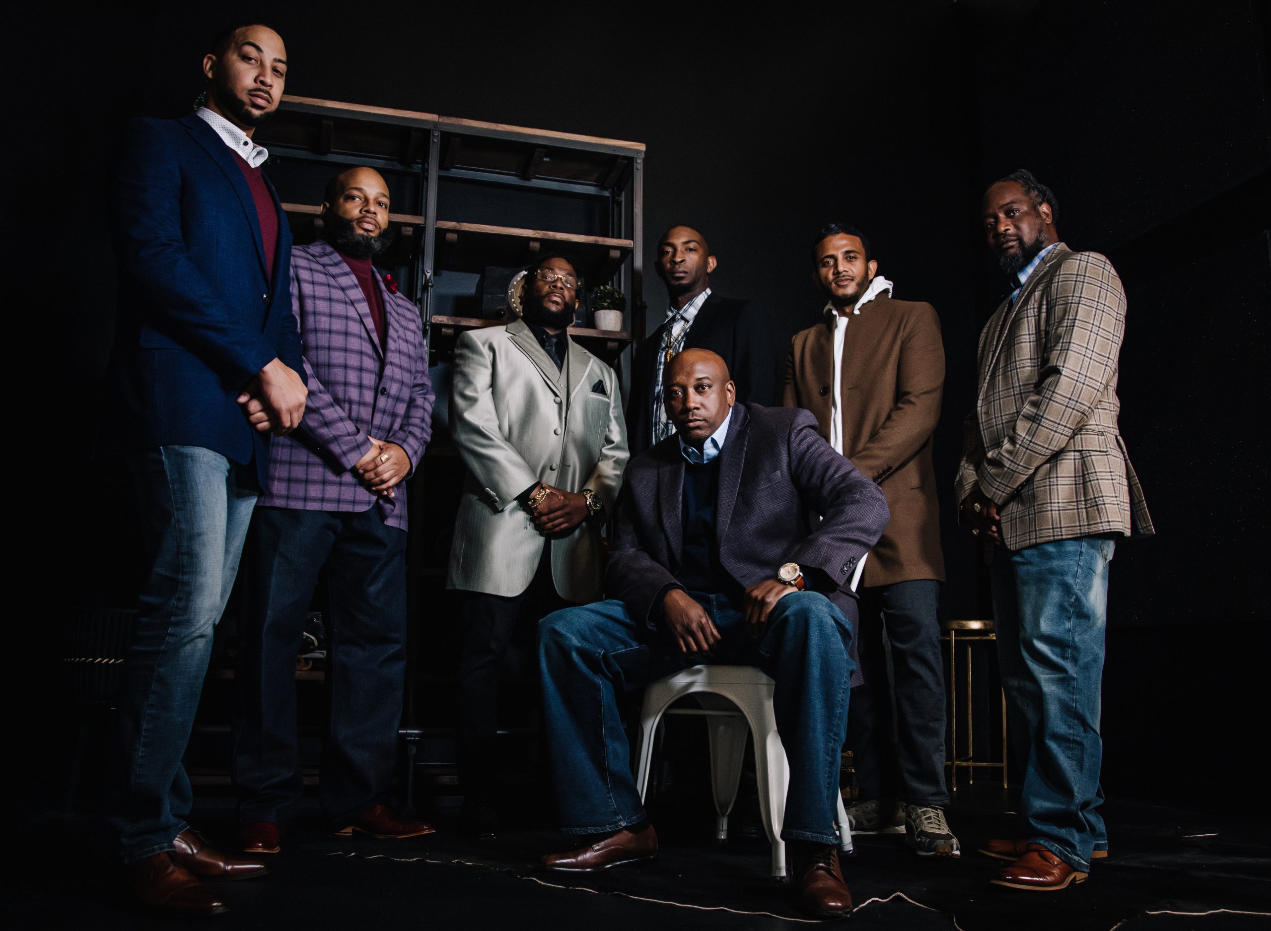 The U Talk Sports Show crew — seven men suited up around a single chair in the black-room studio